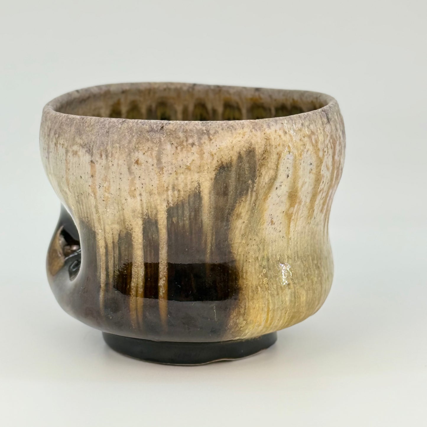 Ceramic bowl with brown and beige glaze on a white background