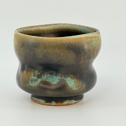 Ceramic cup with green and brown glaze on a white background