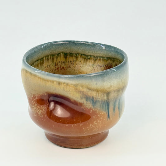 Ceramic cup with multicolored glaze on a white background